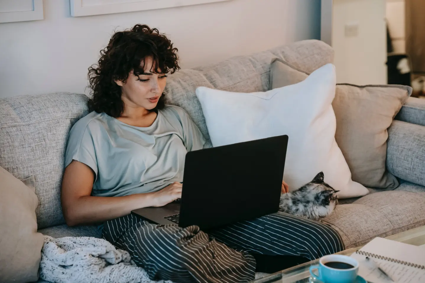 Coverage Gal Best A young woman relaxes on a comfy couch, typing on her laptop.