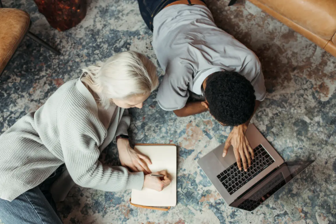 Rewrite Notes Best Relaxing on a carpeted floor, a young man and woman work on a laptop together.