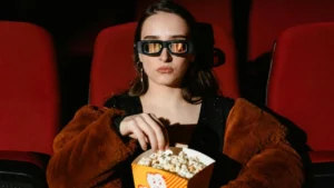 Bored filmgoer watching movie in a fur coat and mirrored sunglasses.